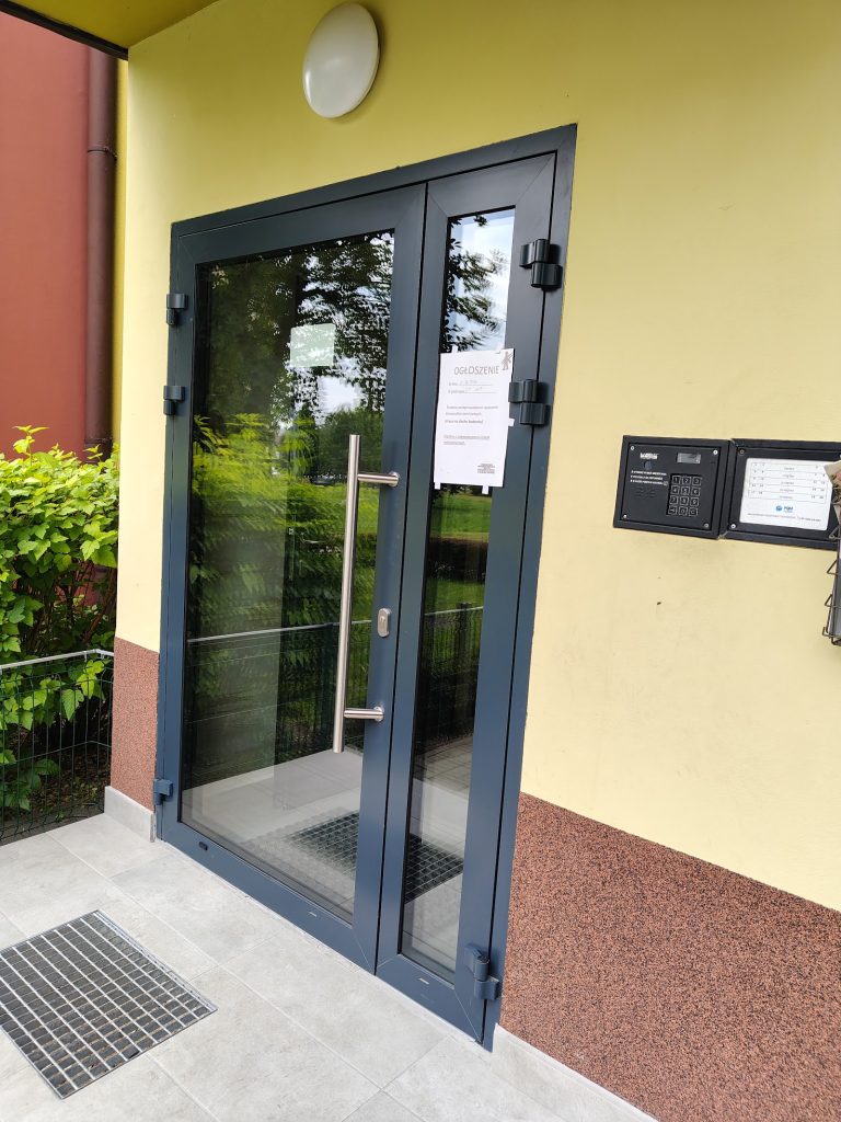 Dwuskrzydłowe drzwi aluminiowe do klatki schodowej z uchwytem poziomym – wejście do wspólnoty mieszkaniowej