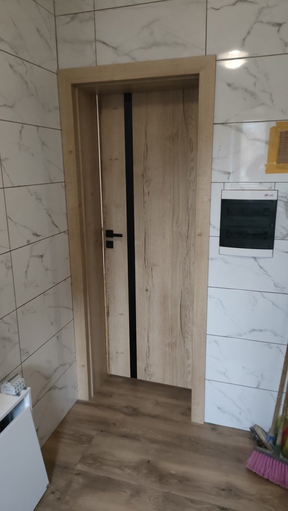Drzwi wewnętrzne Vivento Astoria Black w kolorze dąb Halifax w łazience wykończonej białym marmurem, zbliżenie